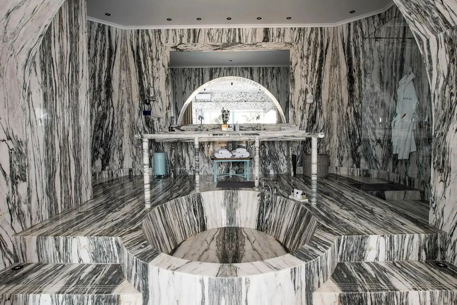 Badezimmer komplett aus gemustertem Marmor mit einer eingelassenen runden Badewanne und Waschtisch.