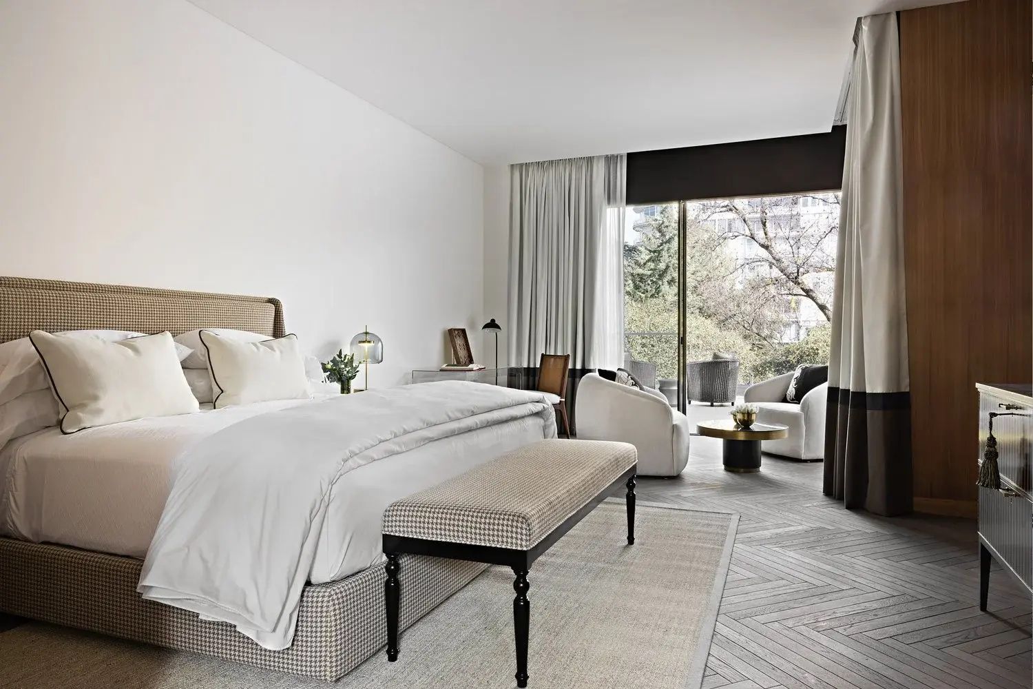 Helles Hotelzimmer mit Doppelbett, Sitzbereich und Balkontür ins Grüne.