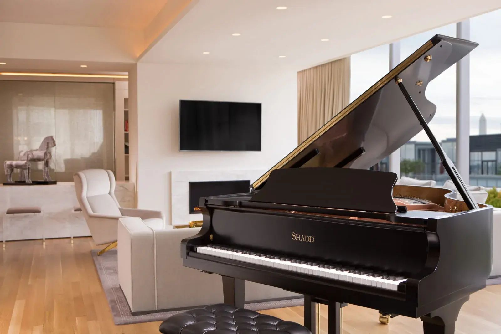 Schwarzer Flügel im Wohnbereich einer Suite mit Sessel und Kamin im Hintergrund.