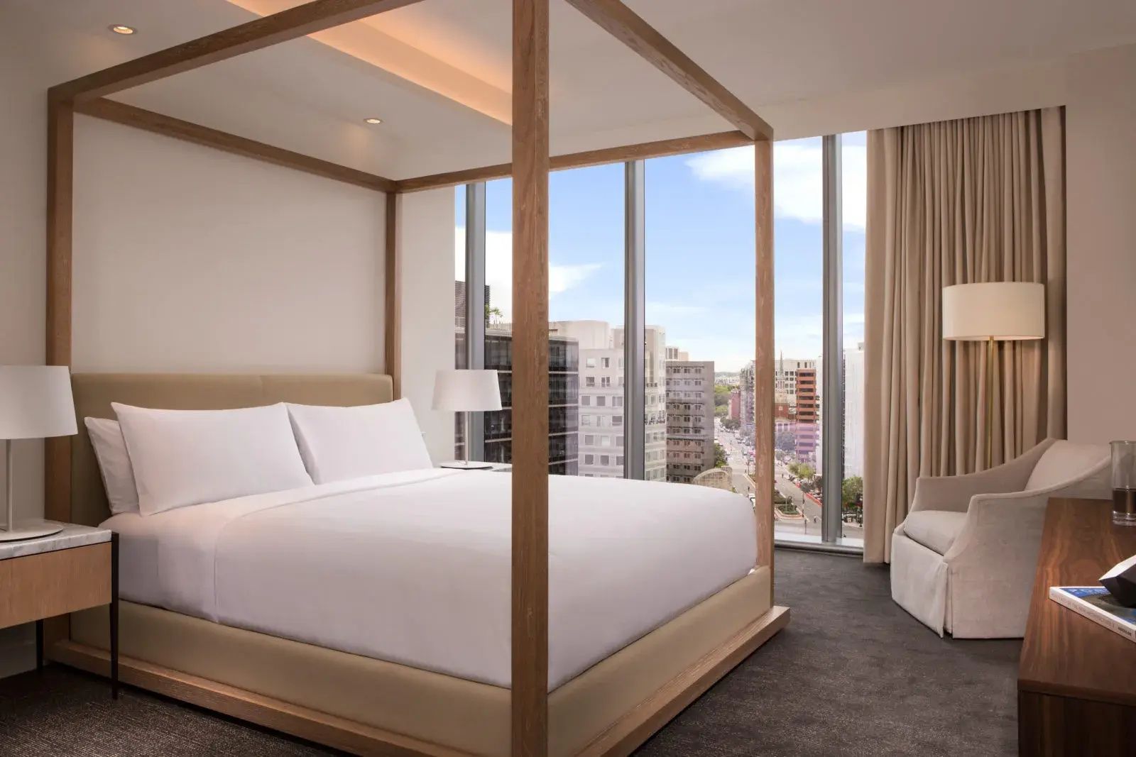 Schlafzimmer mit einem großen Himmelbett aus Holz und bodentiefen Fenstern mit Stadtblick.