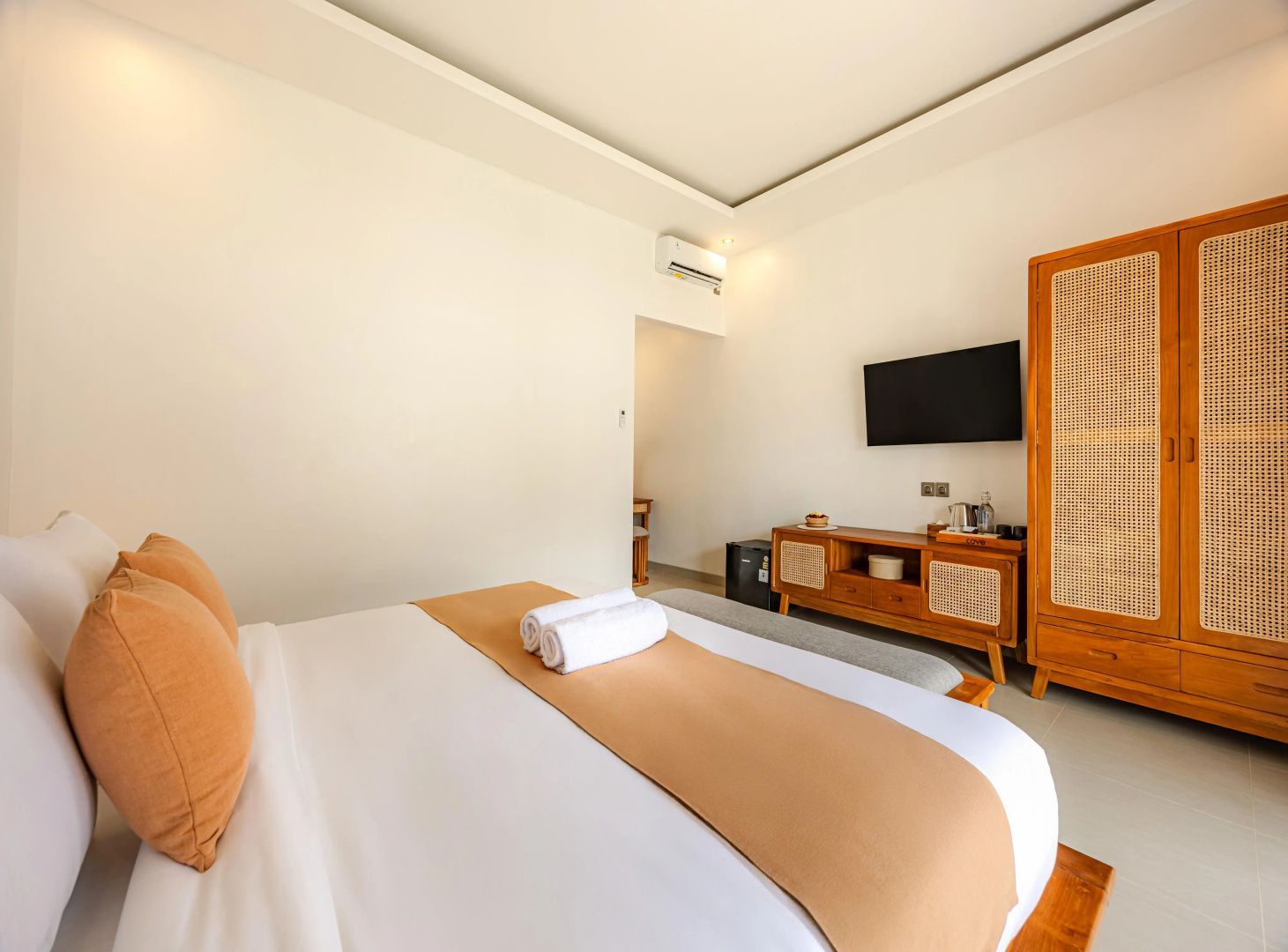 Blick im Hotelzimmer auf ein Holzboard mit Fernseher und einen Kleiderschrank aus Holz.