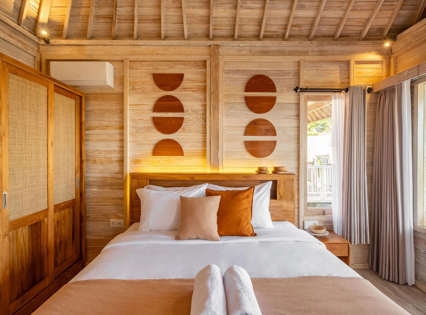 Gemütliches Bungalowzimmer mit Holzverkleidung, Doppelbett und Wanddekoration aus Holz.