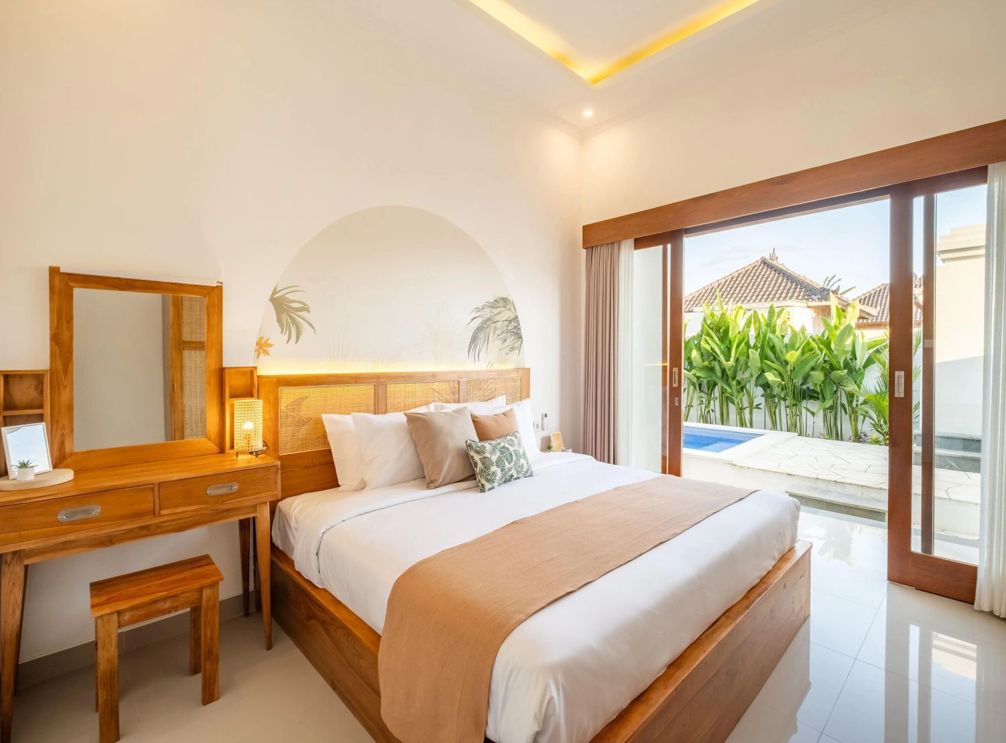 Schlafzimmer mit Holzdoppelbett und Blick auf Terrasse sowie Pool.