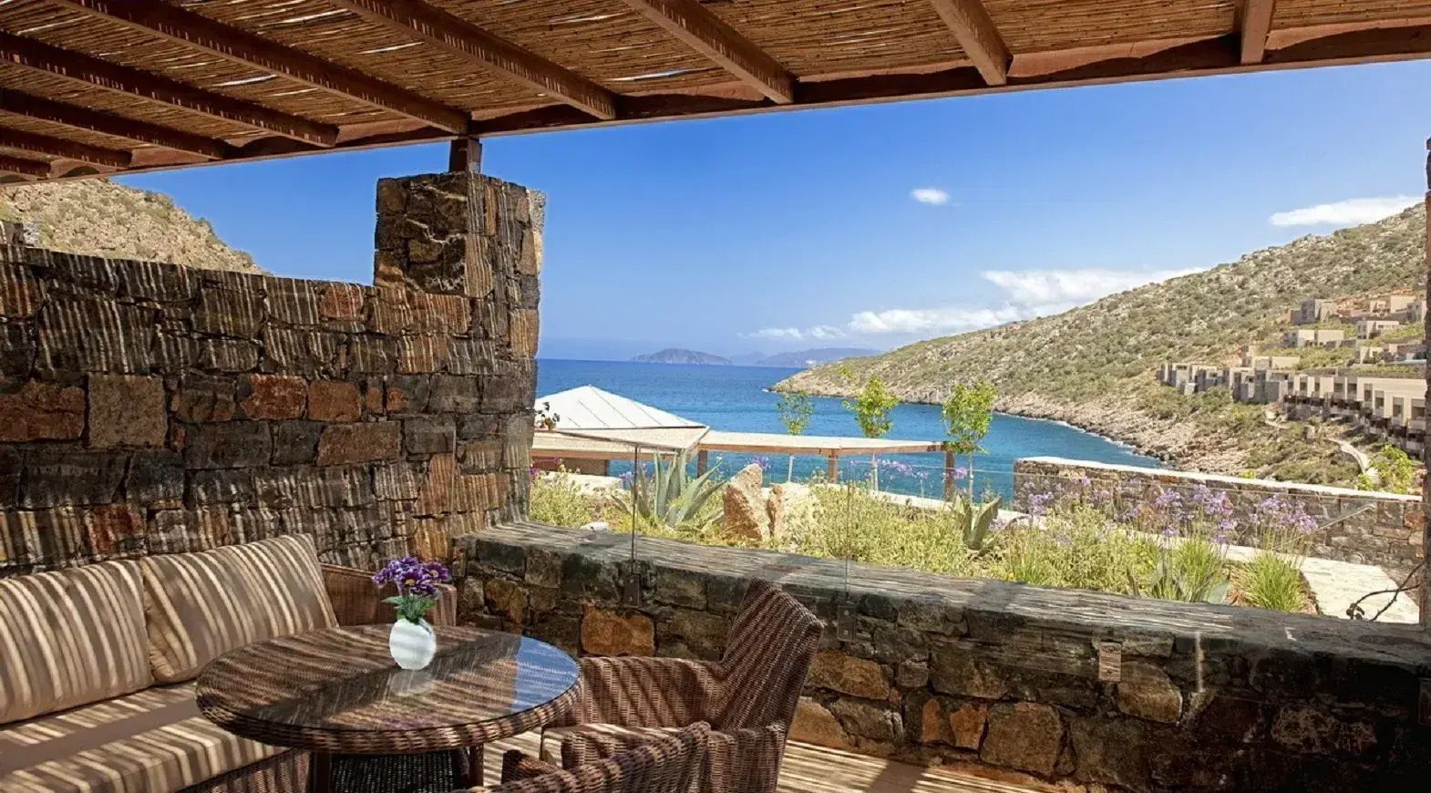 Überdachte Terrasse mit Sitzgelegenheit und Blick auf die Bucht und das Meer.