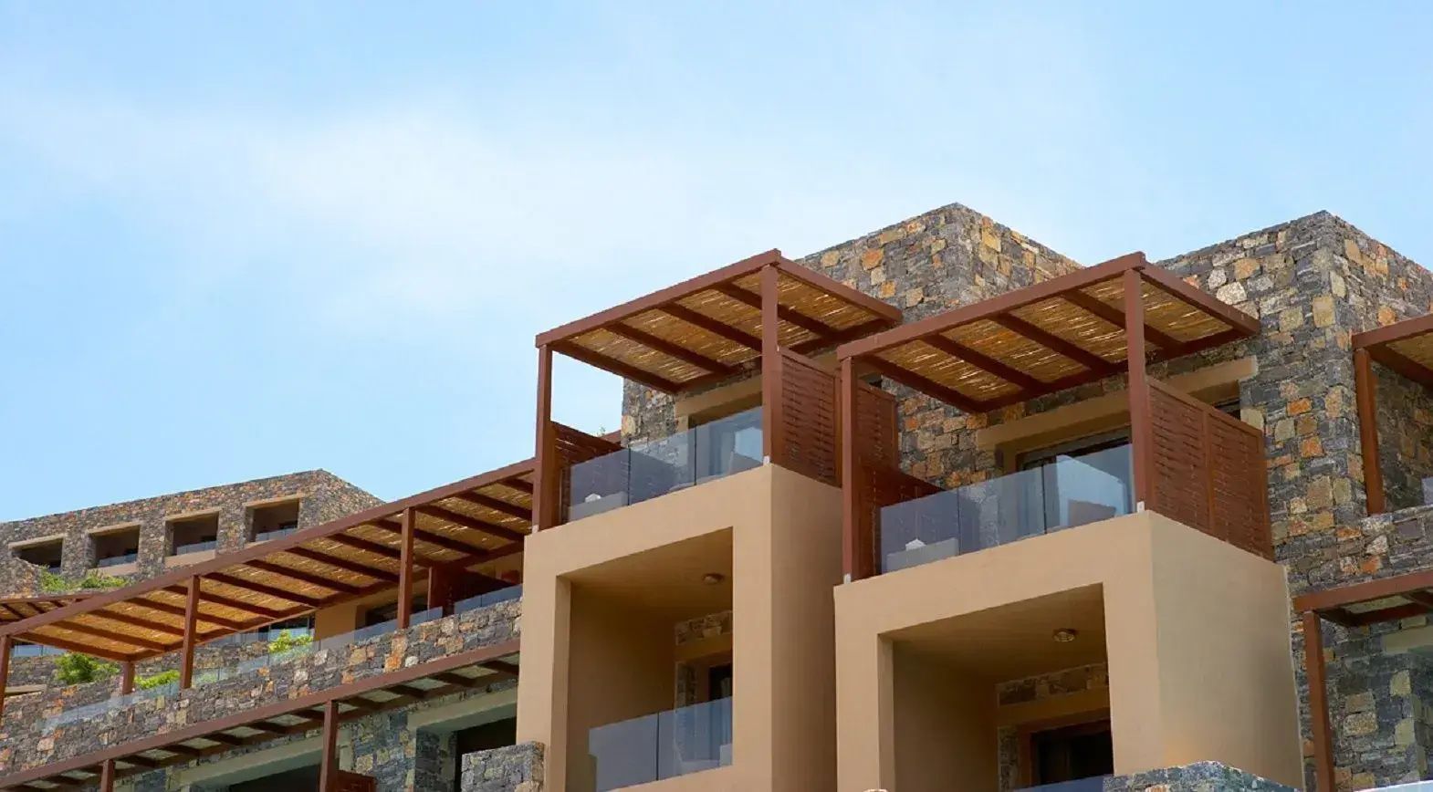 Moderne Hotelarchitektur aus Naturstein und beigefarbenen Elementen mit geschützten Balkonen.