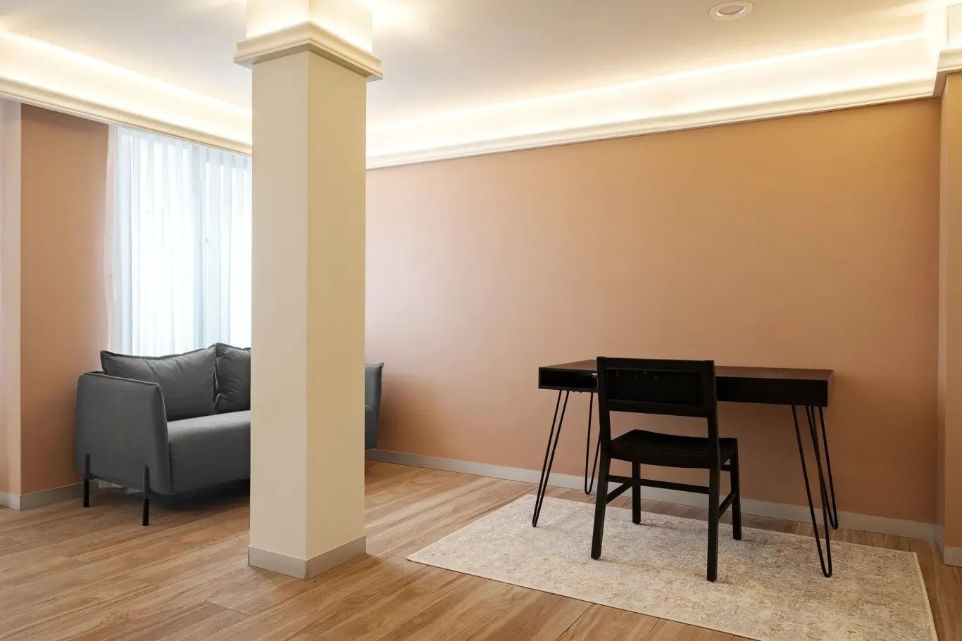 Arbeitsbereich mit schwarzem Schreibtisch und Stuhl auf Teppich an beigefarbener Wand.