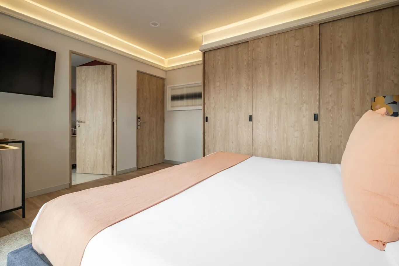 Schlafzimmer mit großem Holzschrank, heller Deckenbeleuchtung und Türen.