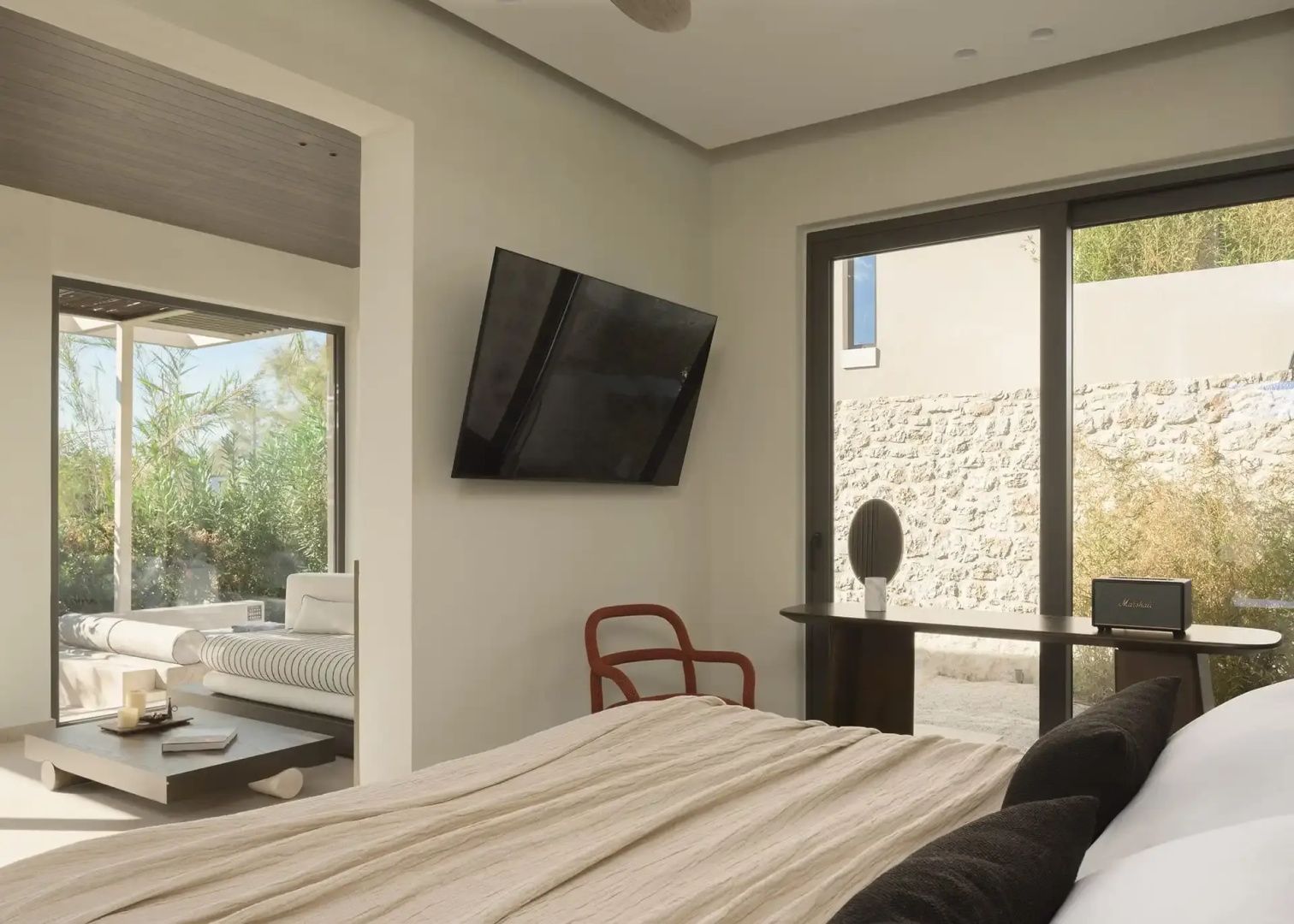 Helles Schlafzimmer mit Bett im Vordergrund, TV an der Wand und Blick ins Nebenzimmer.
