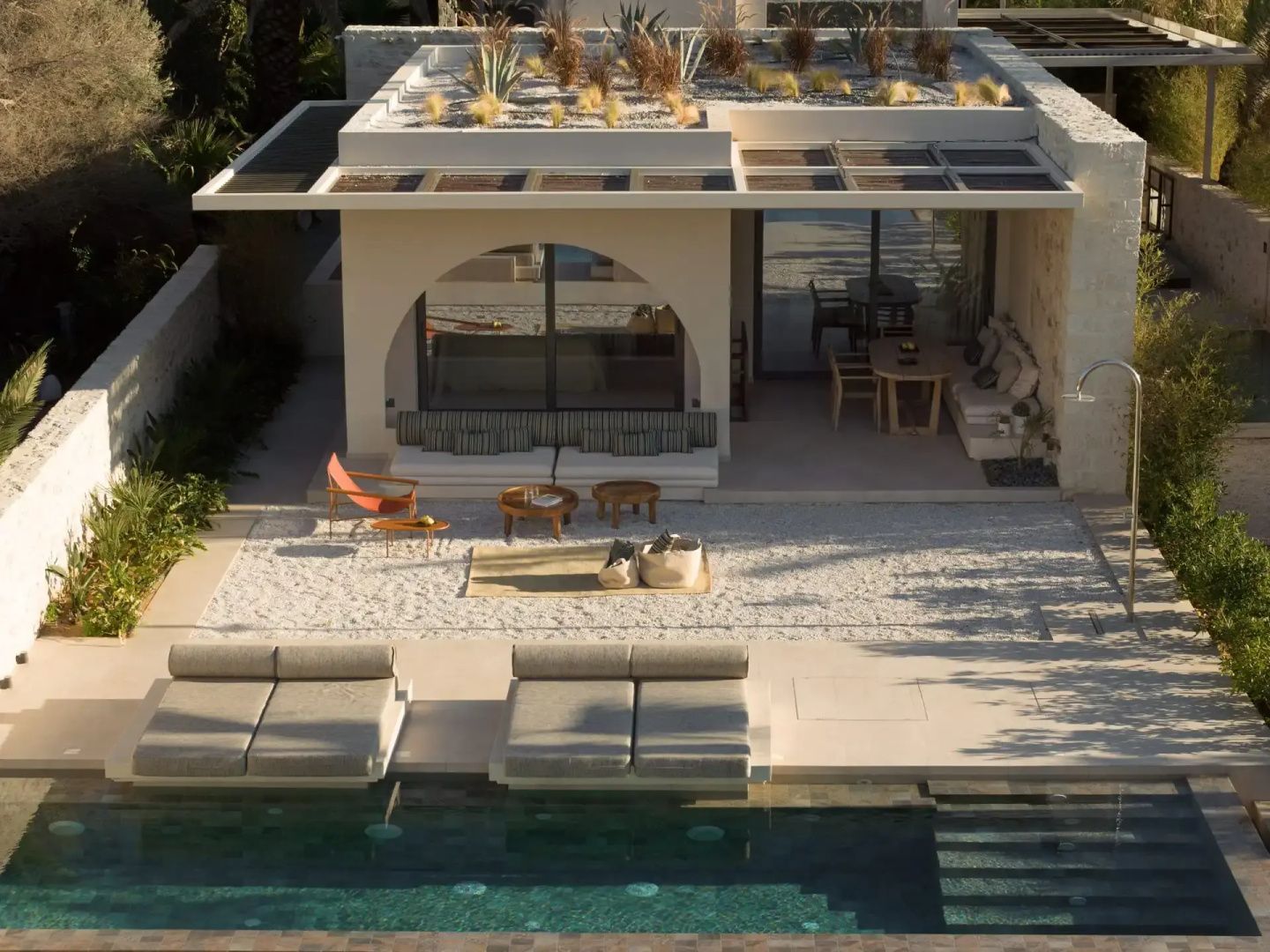 Außenansicht einer Terrasse mit Sitzbereich, Liegestühlen und einem angrenzenden Pool.