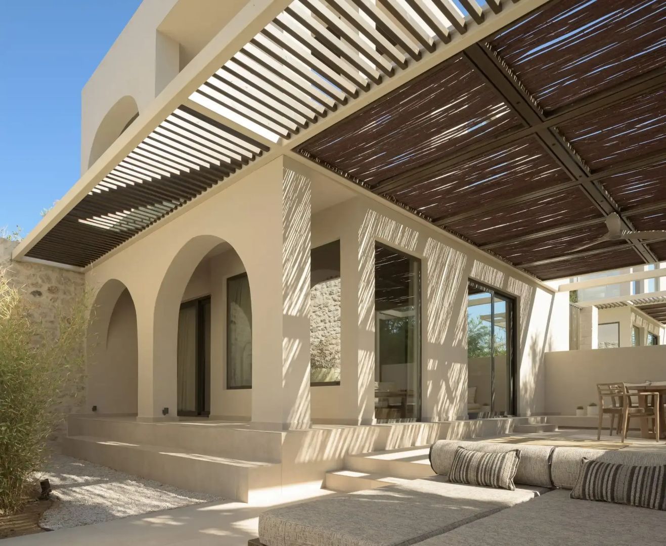 Modernes Gebäude mit Bogenarchitektur, überdachter Terrasse und Tagesbett.