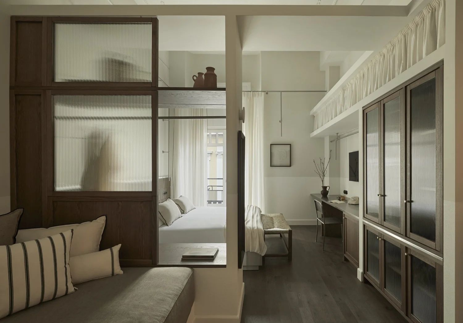 Geräumiges Hotelzimmer mit Sitzecke, Schreibtisch und abgetrenntem Schlafbereich.
