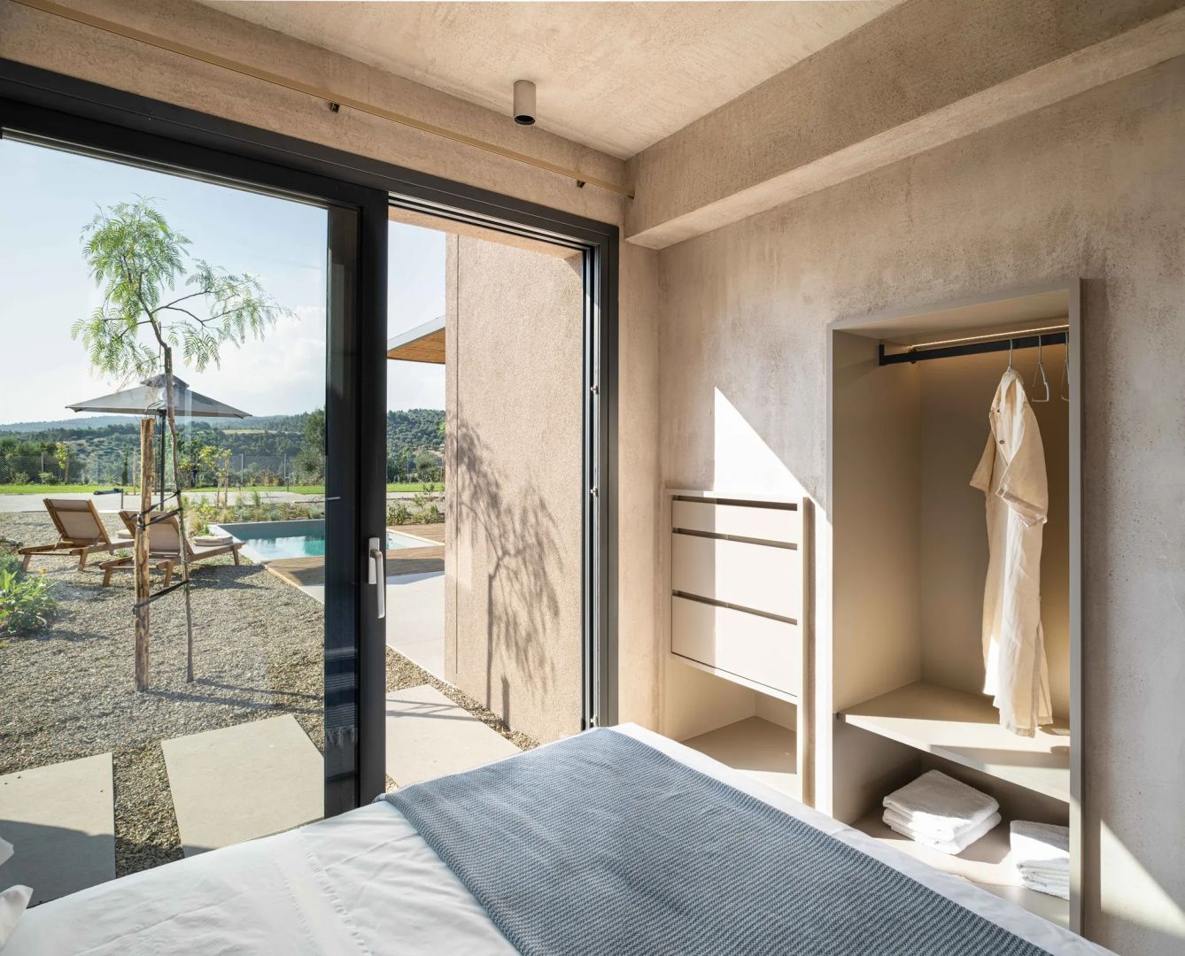 Zimmerbereich mit offenem Schrank, Bademantel und Glastür zur Terrasse mit Pool.