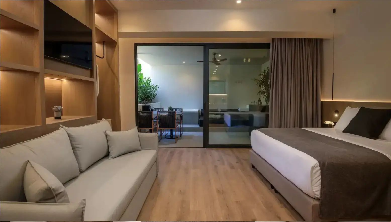 Geräumiges Schlafzimmer mit Bett, Sofa und Glasfront zur Außenterrasse.