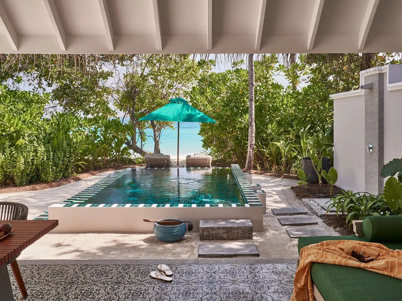 Privater Pool auf einer Sandterrasse mit Sonnenschirm und Blick aufs Meer.