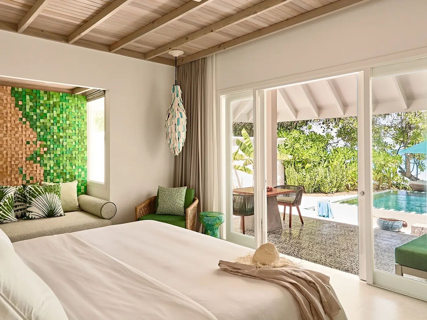 Schlafzimmer mit weißem Bett, grünen Akzenten und Zugang zur Terrasse.