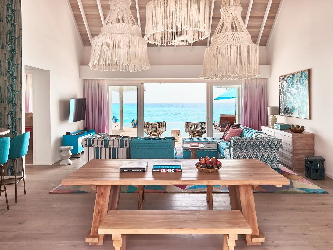 Offener Wohnbereich einer Villa mit Holztisch, großem Sofa und Blick aufs Meer.