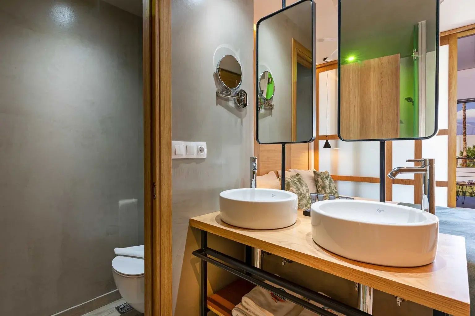 Modernes Badezimmer mit zwei Aufsatzwaschbecken, Spiegeln und angrenzendem WC-Bereich.