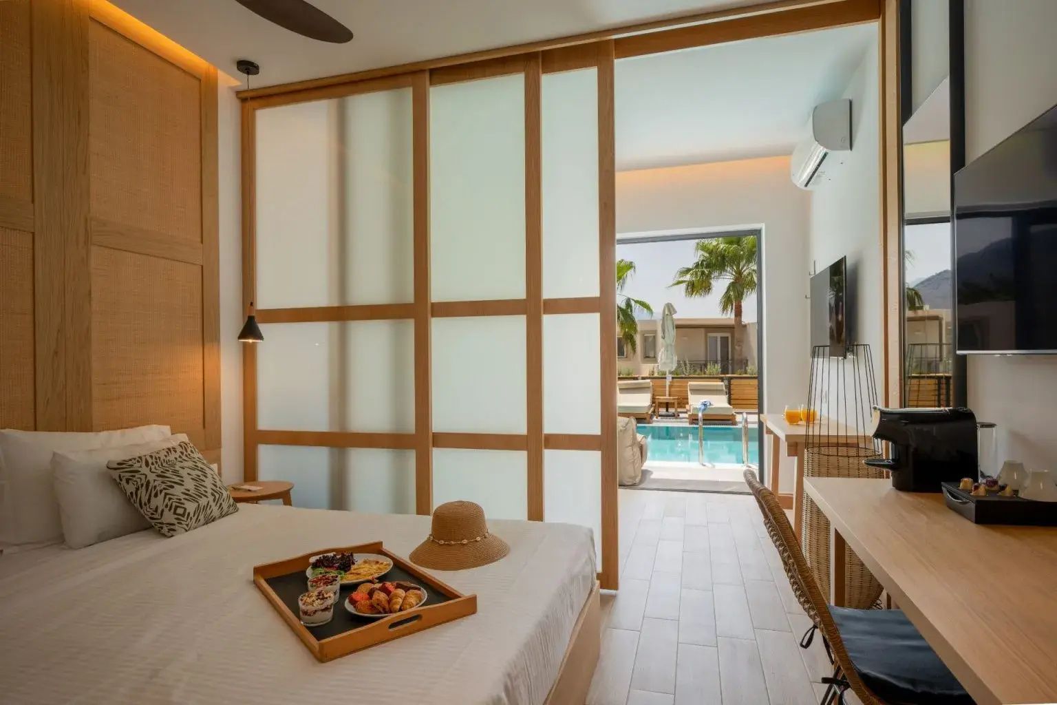 Modernes Hotelzimmer mit Bett, Schiebetür aus Holz und Zugang zum Außenpool.