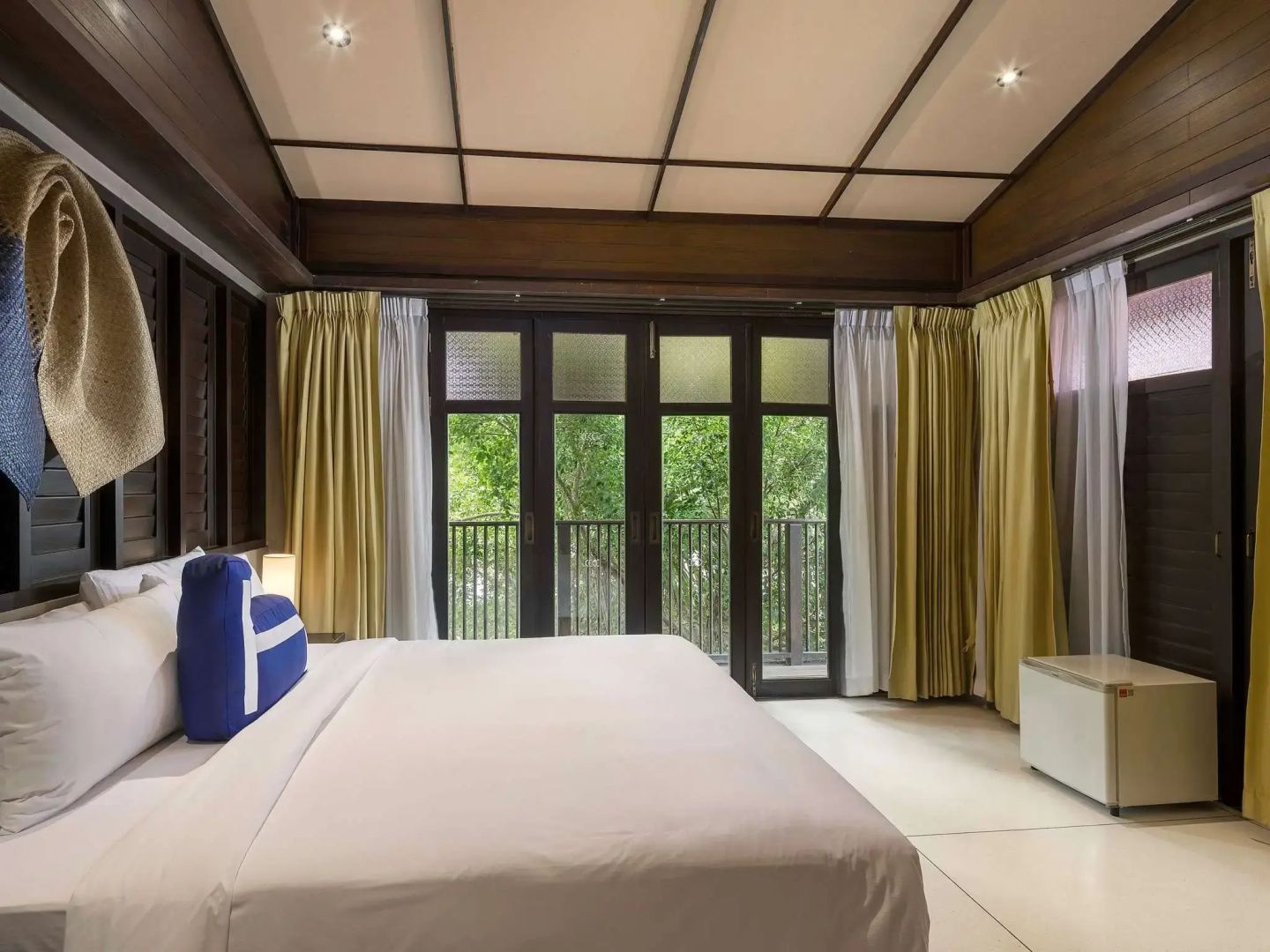 Helles Hotelzimmer mit großem Doppelbett, Holzdecke und Glastüren zum Balkon