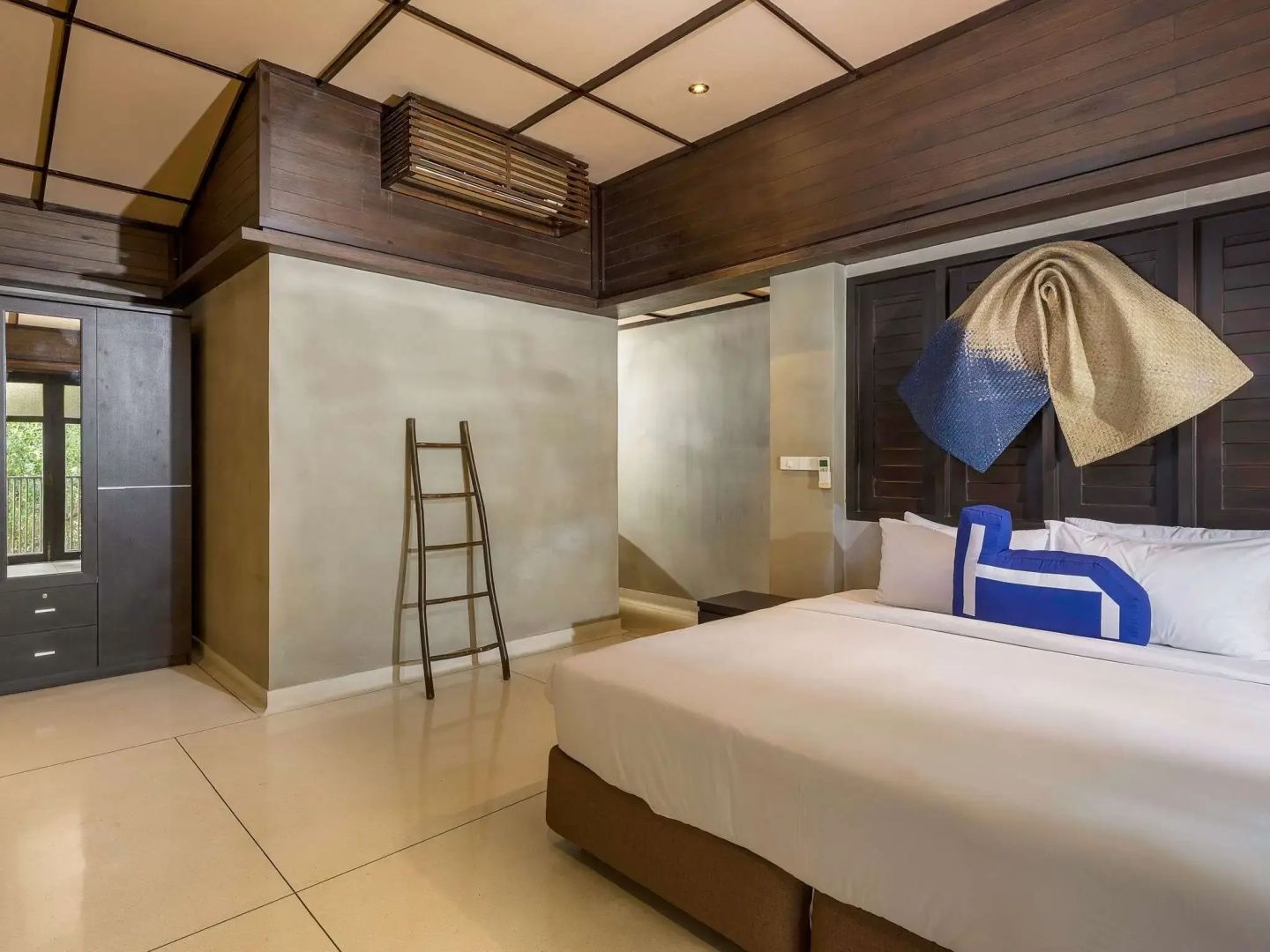 Geräumiges Hotelzimmer mit Holzdecke, großem Bett und hölzerner Dekoleiter