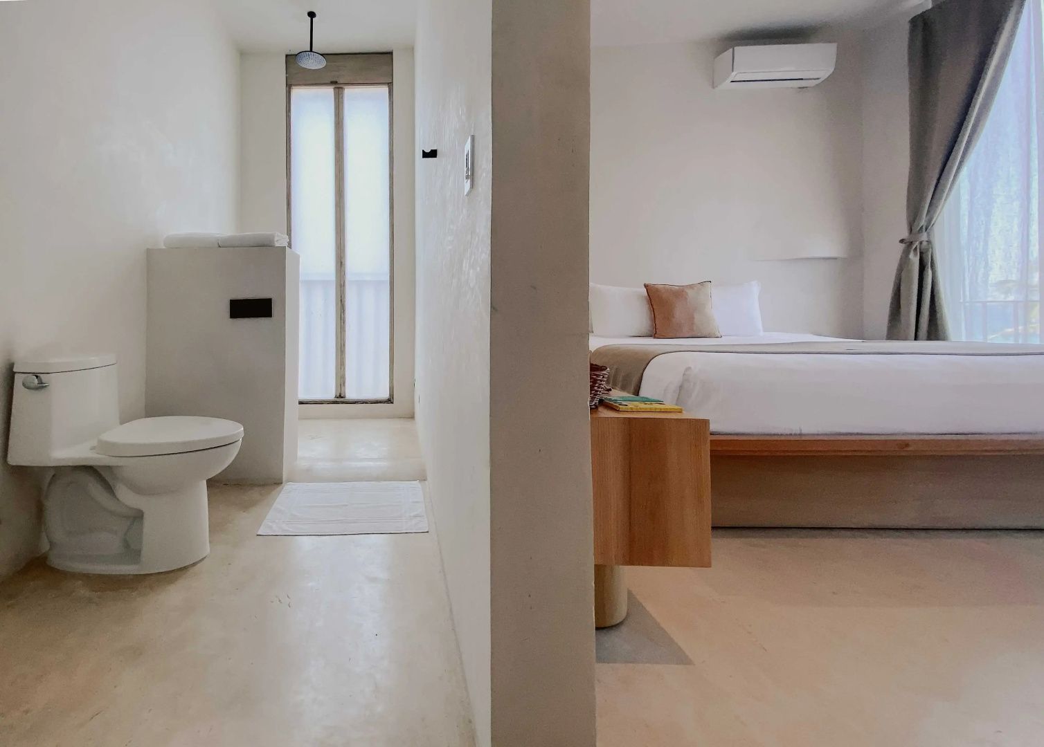Blick auf das Badezimmer mit WC und den direkt angrenzenden Schlafbereich des Hotelzimmers.