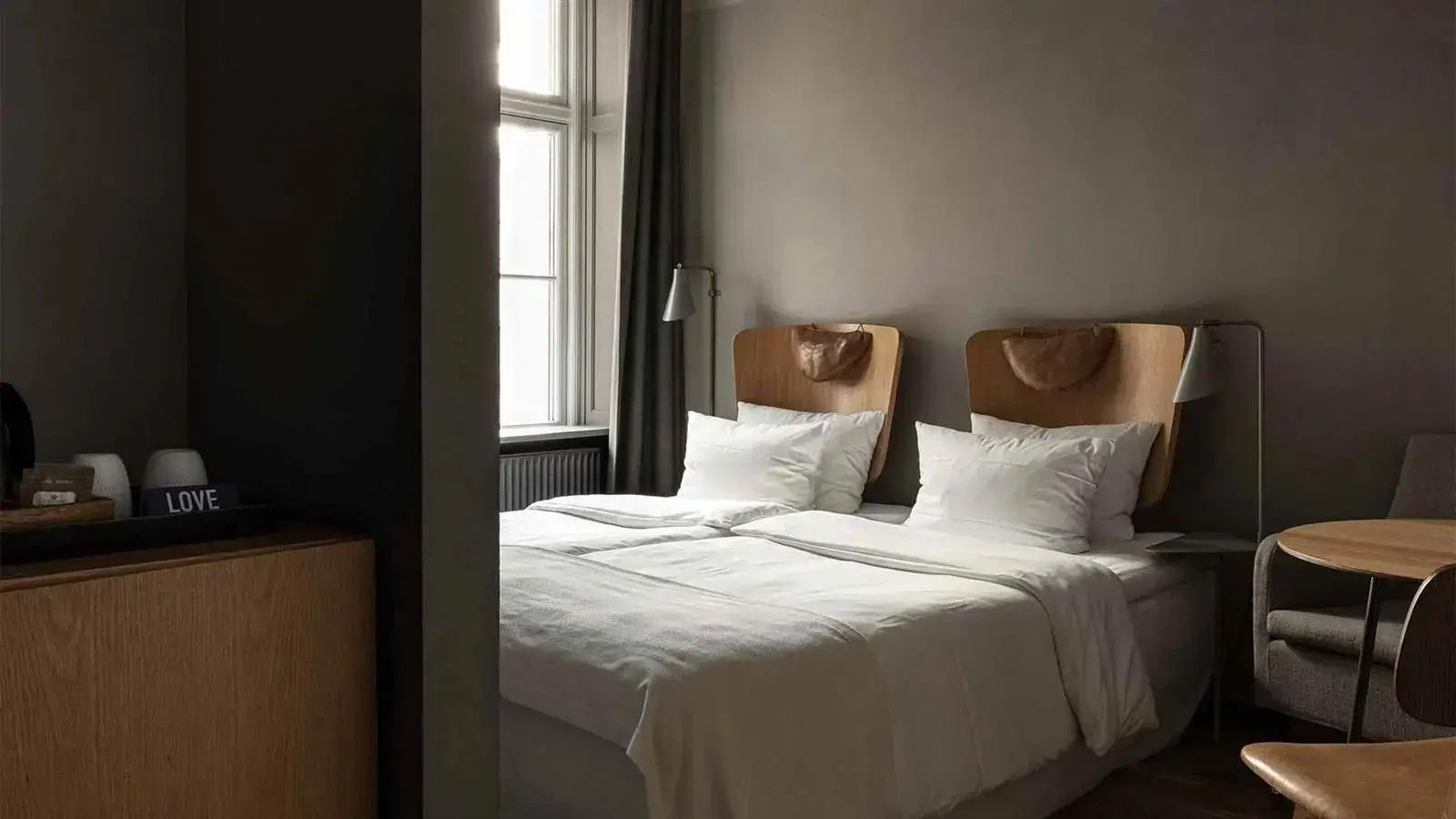 Helles Schlafzimmer mit Doppelbett, weißen Kissen und Kopfstützen aus Holz.