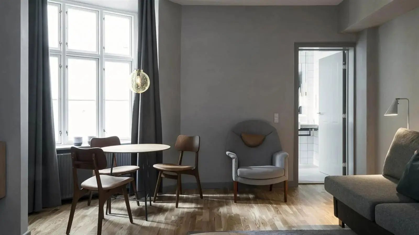 Sitzecke im Hotelzimmer mit rundem Esstisch, Stühlen und Sessel.