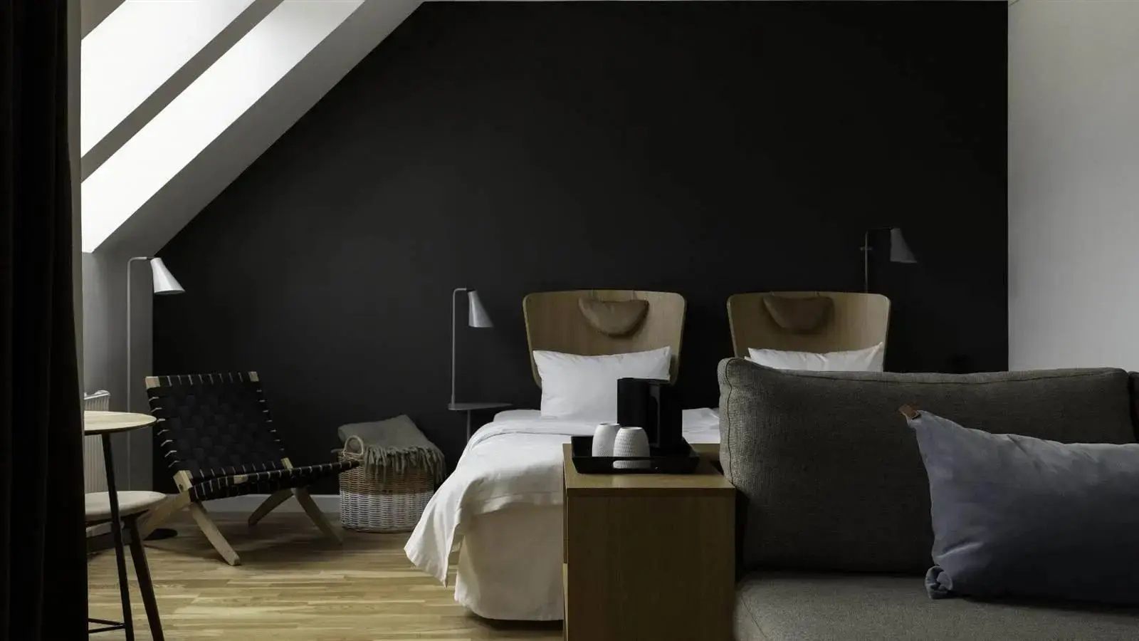 Hotelzimmer unter einer Dachschräge mit dunkler Wand und Doppelbett.