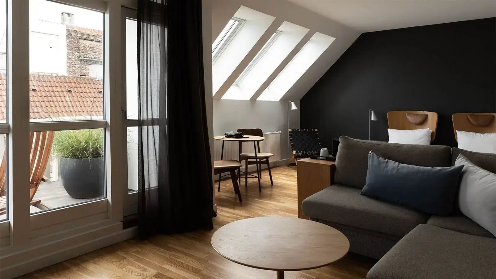 Wohnbereich in einem Dachgeschosszimmer mit Dachfenstern, Sitzecke und Holzboden.