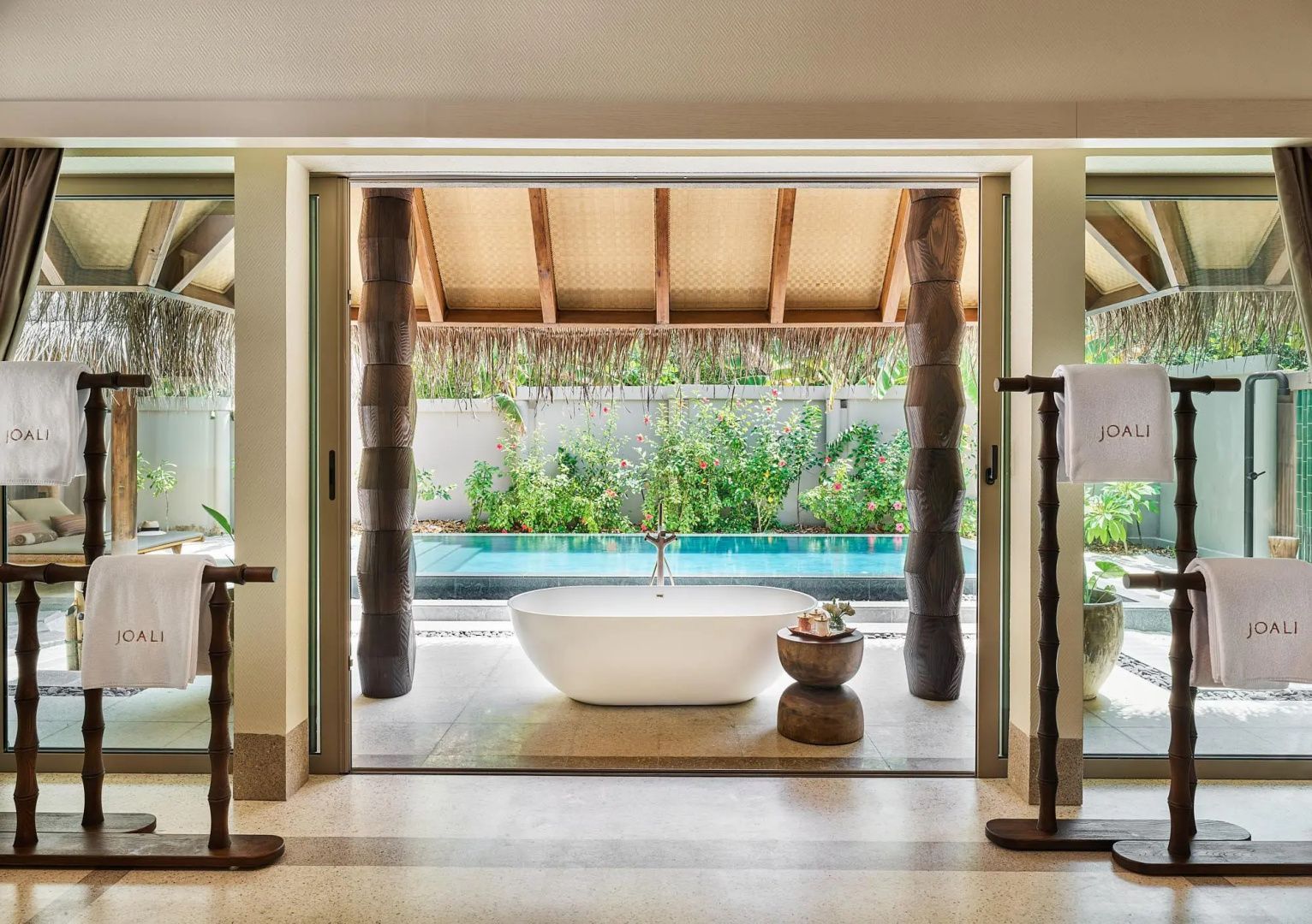 Freistehende Badewanne im Badezimmer mit Blick auf einen kleinen Pool im Aussenbereich.