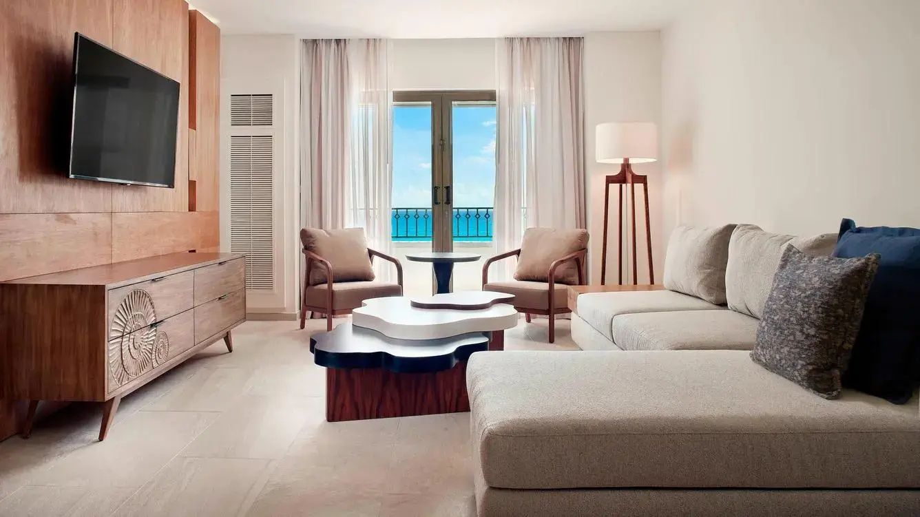 Wohnbereich eines Hotelzimmers mit Couch, Sesseln, Couchtisch und Ausblick auf das Meer.