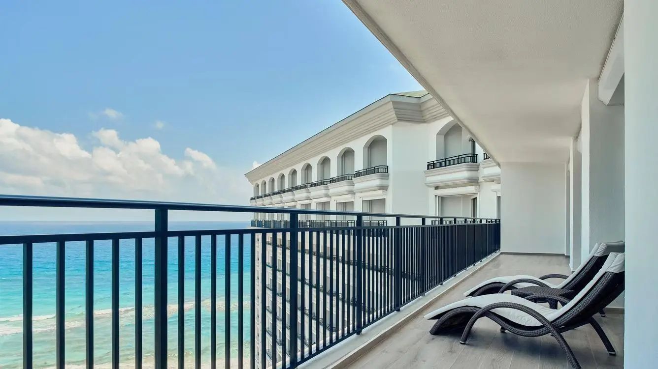 Balkon mit Liegestühlen und Blick auf die Hotelfassade sowie das angrenzende Meer.