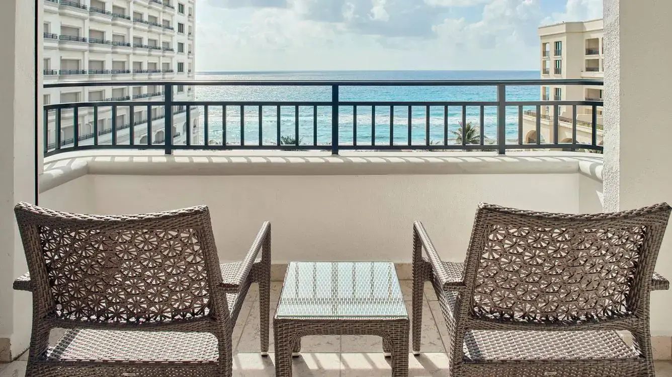 Sitzbereich auf dem Balkon mit zwei Stühlen und Beistelltisch vor dem blauen Meer.