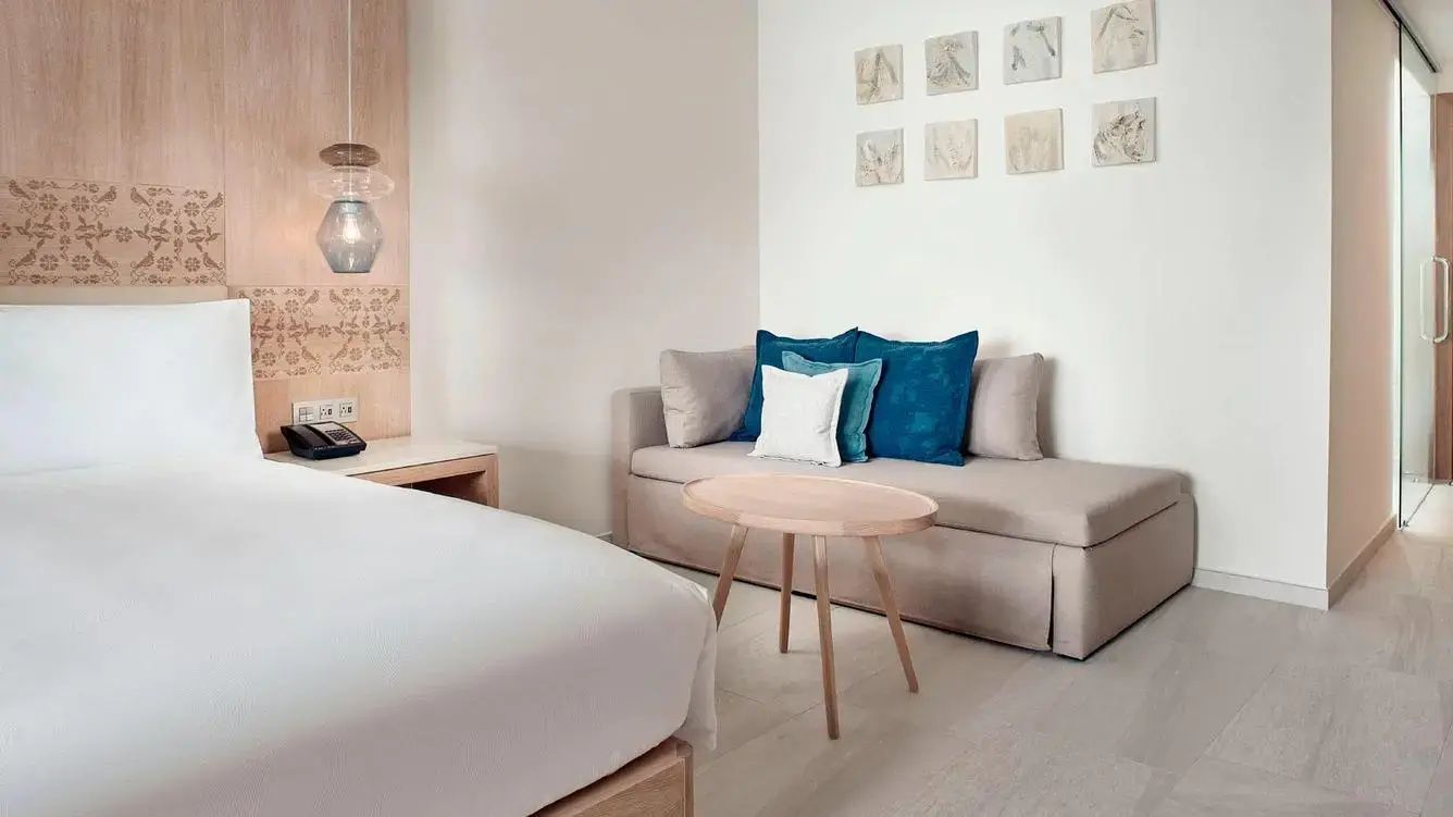 Sitzbereich im Zimmer mit beigefarbenem Sofa, blauem Kissen und einem kleinen Holztisch.