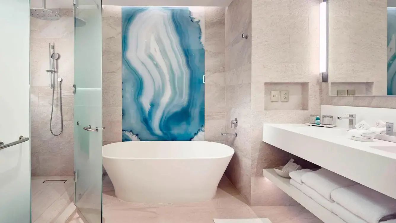 Badezimmer mit einer freistehenden weißen Badewanne und blau gemusterter Wandgestaltung.