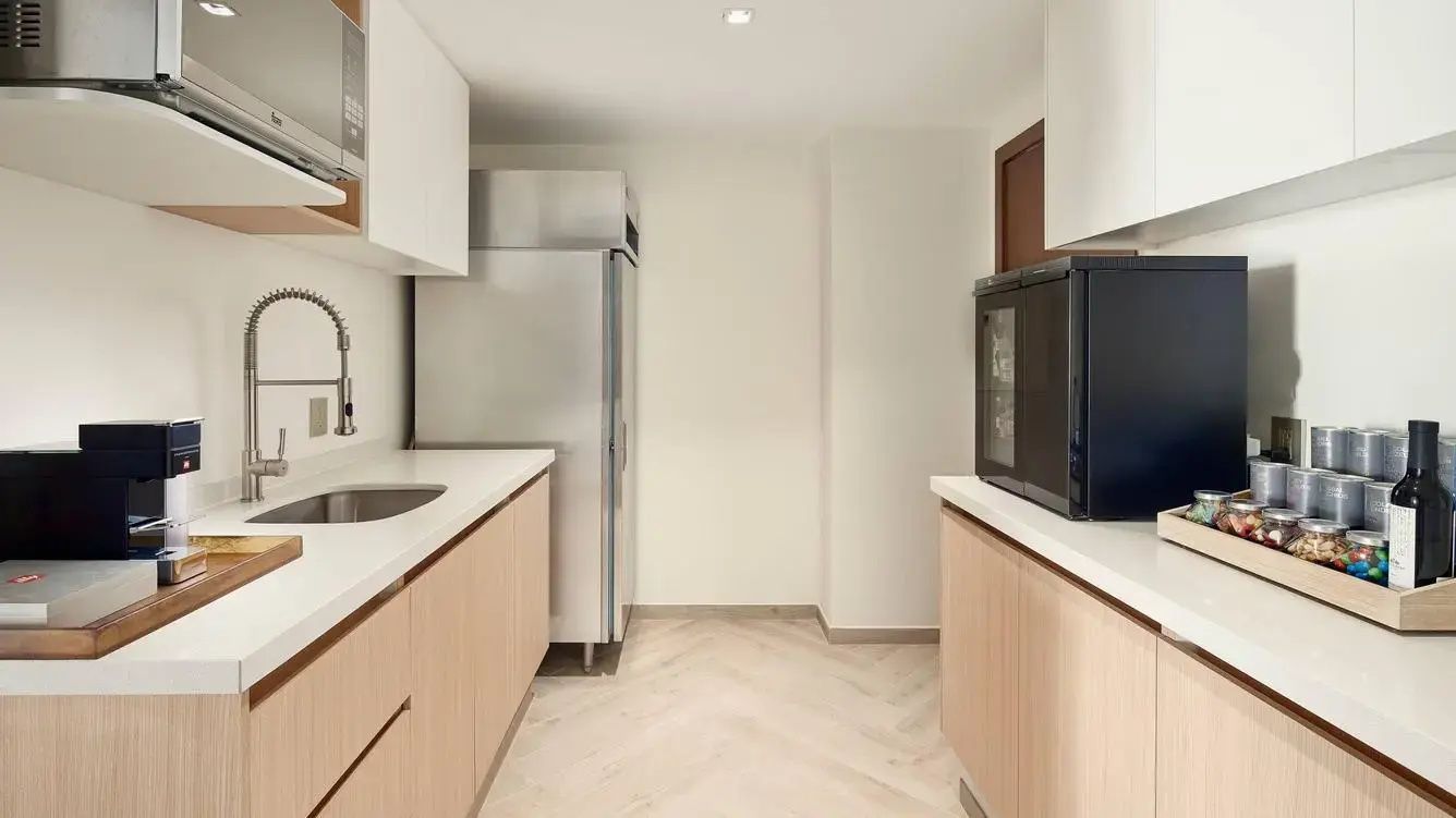 Küche einer Suite mit hellen Holzschränken und einem großen Edelstahlkühlschrank.