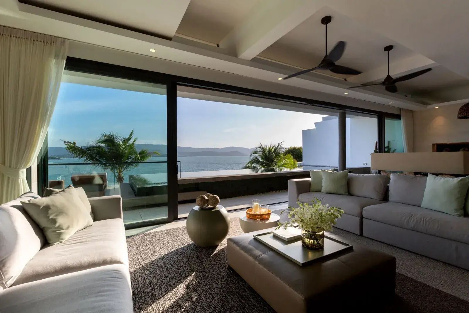 Wohnbereich mit großem Sofa und freiem Blick auf den Pool und das Meer.
