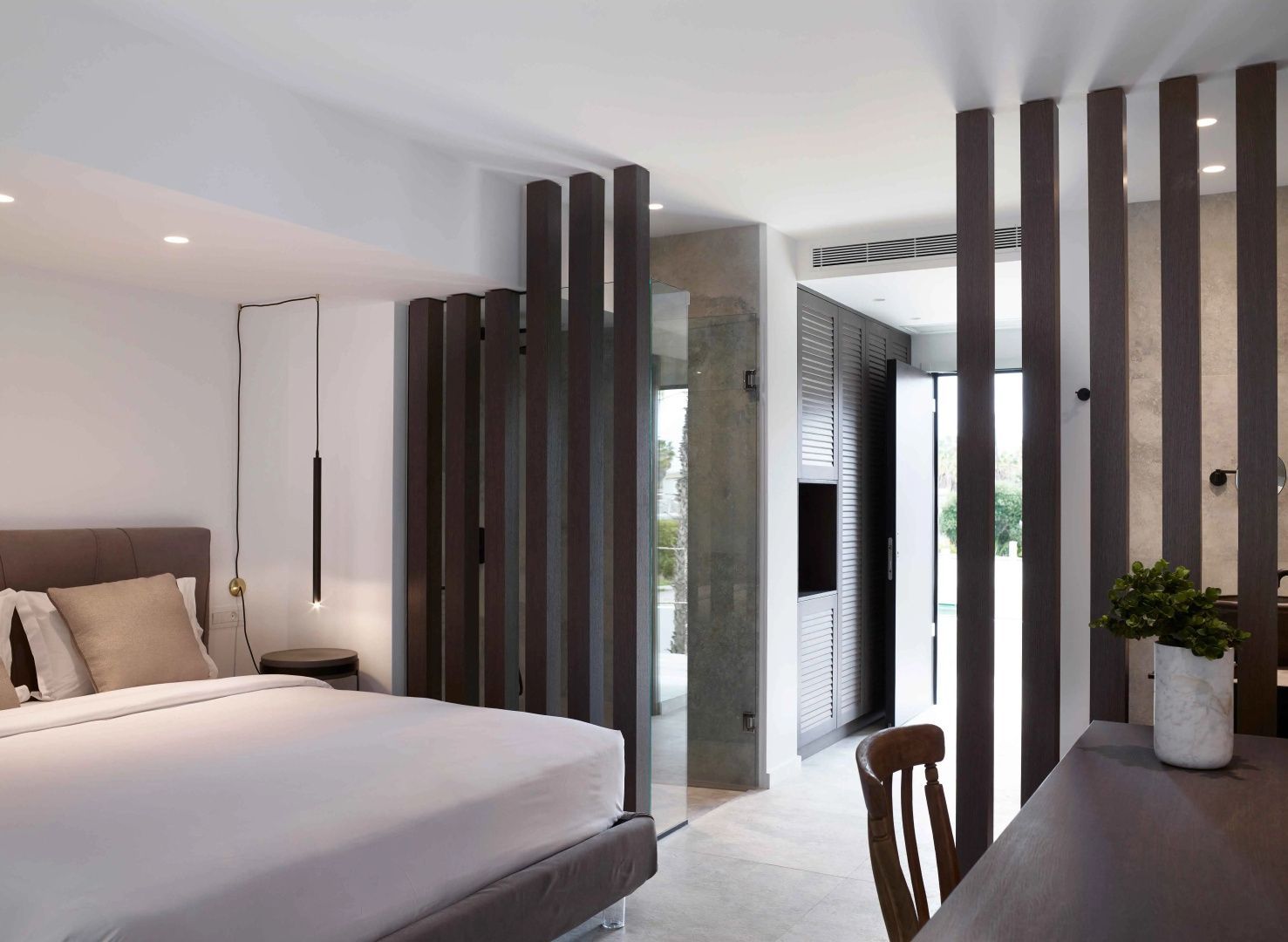 Modernes Hotelzimmer mit Doppelbett und stilvollem Raumteiler aus Holzlamellen.