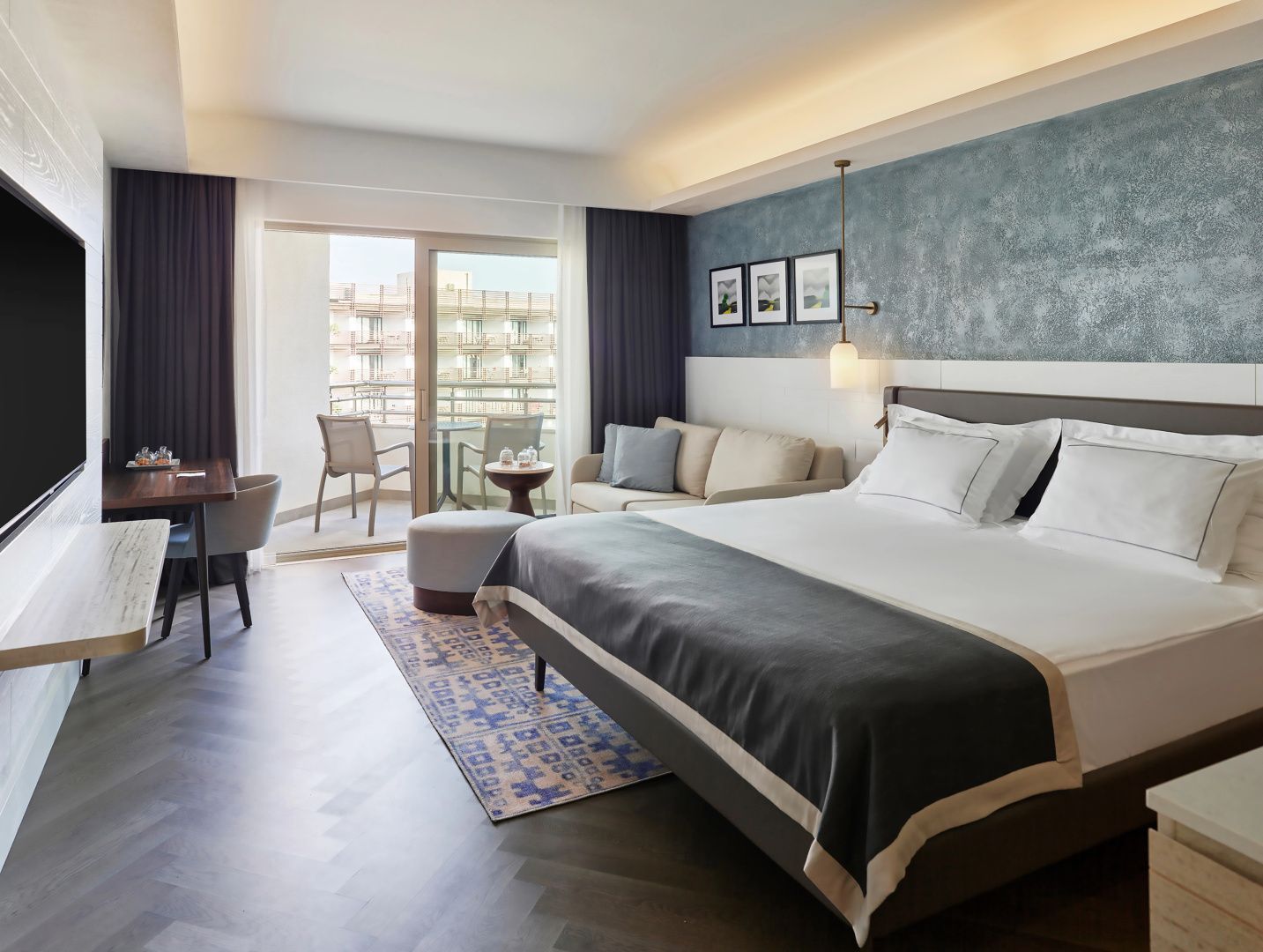 Geräumiges Hotelzimmer mit Doppelbett, einer Sitzecke und Zugang zum Balkon.