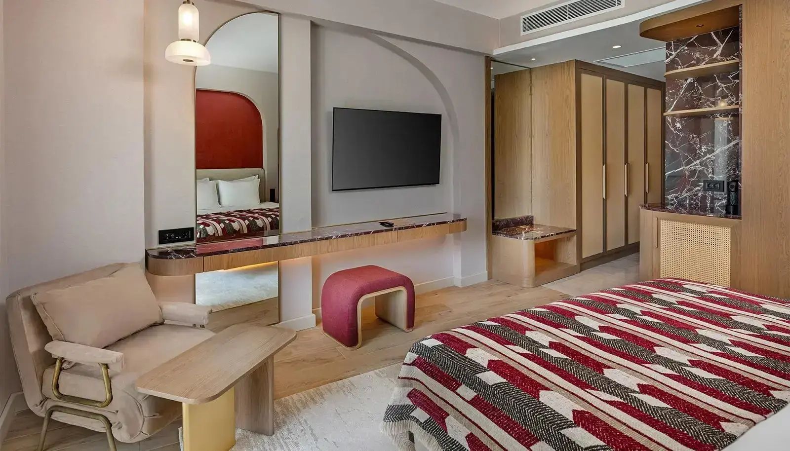 Moderne Inneneinrichtung eines Hotelzimmers mit Fernseher, Spiegel und Hocker.