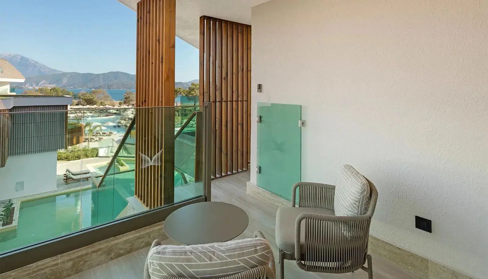 Balkon mit zwei Sesseln und Blick auf die Poolanlage sowie das Meer.
