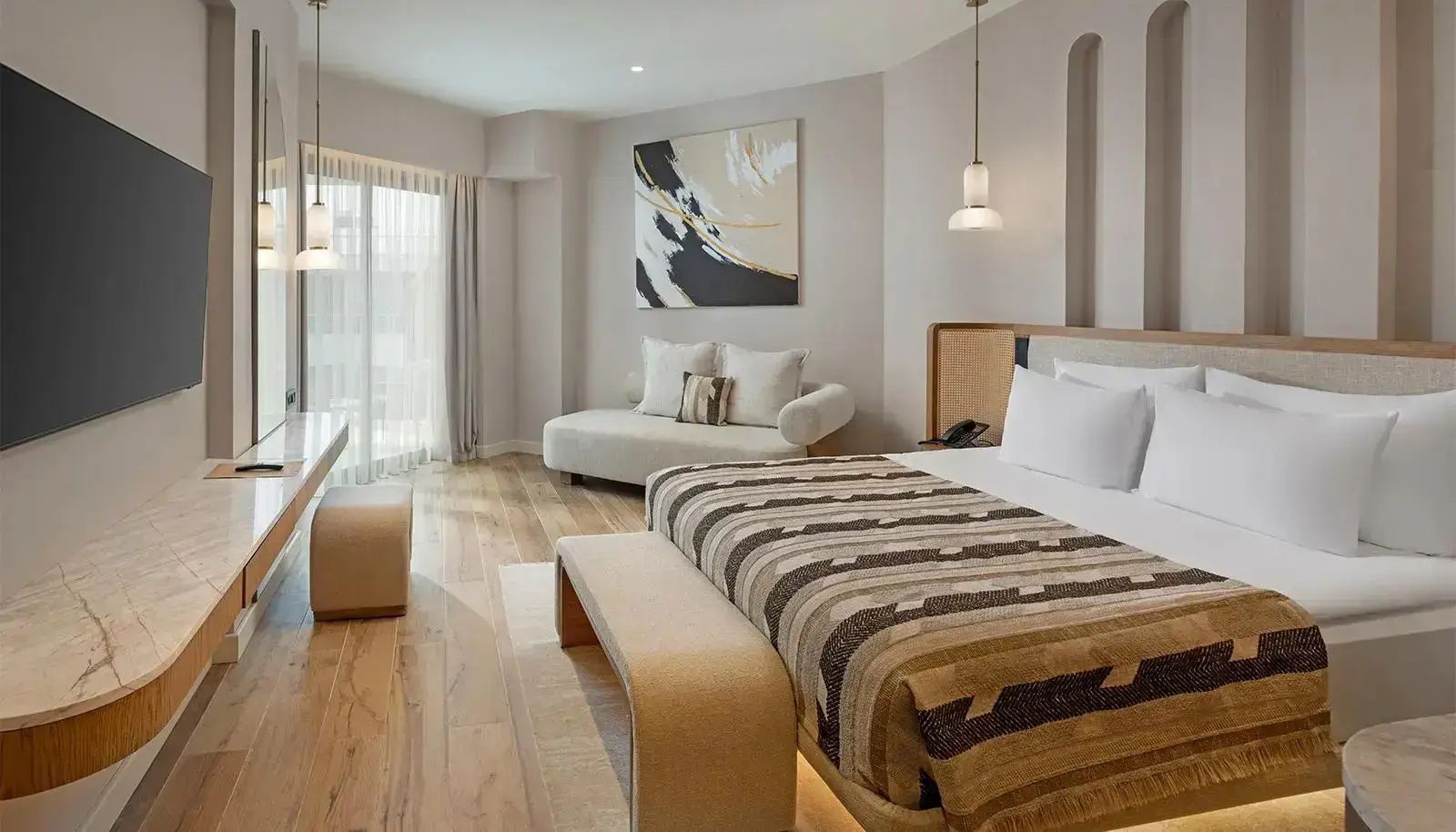 Modernes Hotelzimmer mit Doppelbett, Couch an der Wand und hellem Holzboden.