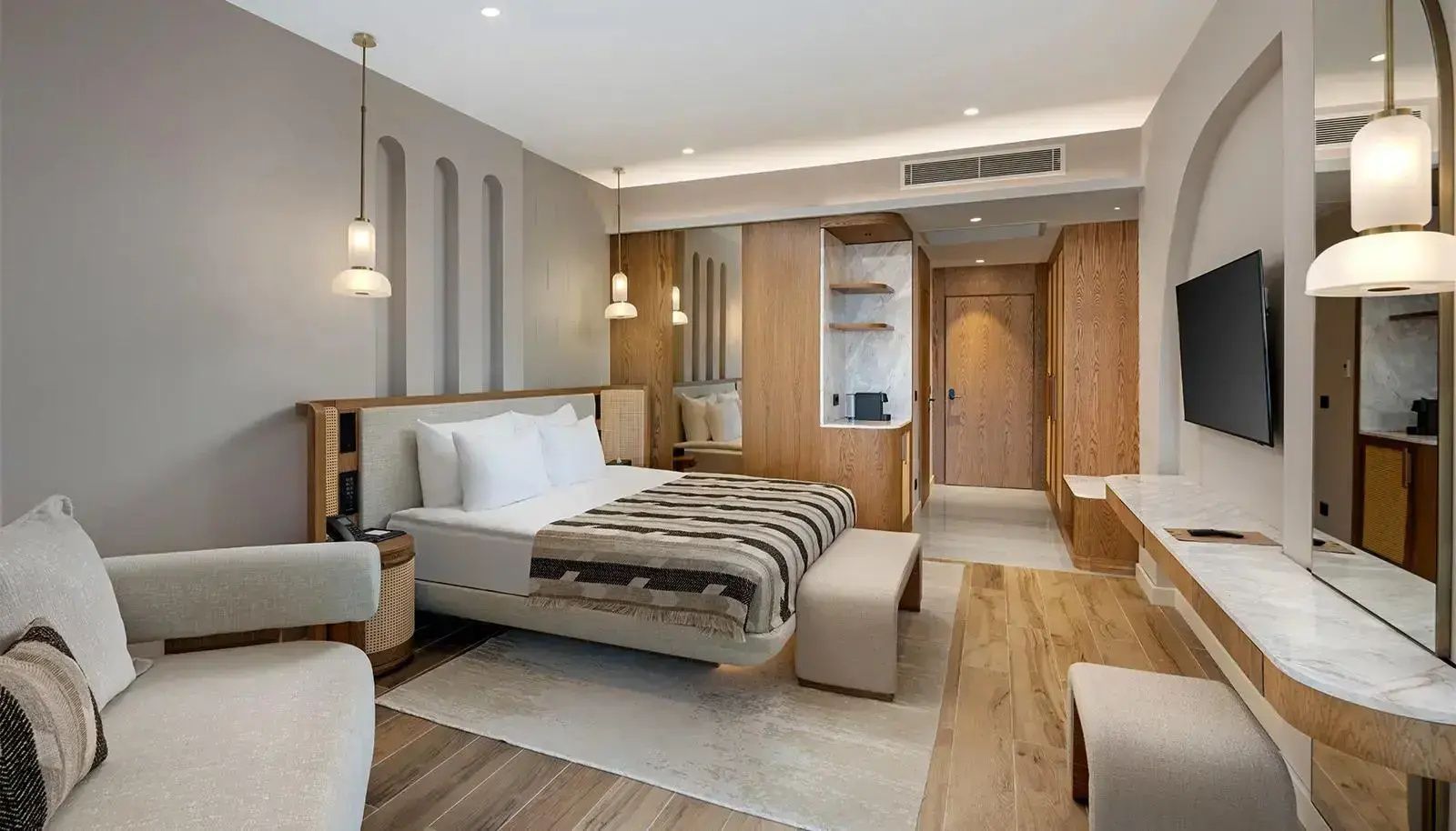 Doppelbett mit gemusterter Decke und Holzverkleidung im Eingangsbereich des Zimmers.