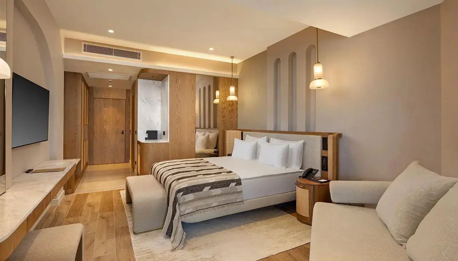 Doppelbett in hellem Hotelzimmer mit Holzelementen und Nachttisch.