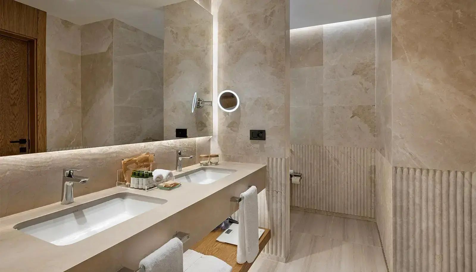 Badezimmer mit zwei Waschbecken, großem Spiegel und beleuchtetem Kosmetikspiegel.
