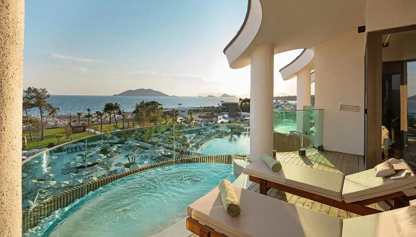 Balkon mit Liegestühlen, Privatpool und Weitblick über die Poolanlage auf das Meer.