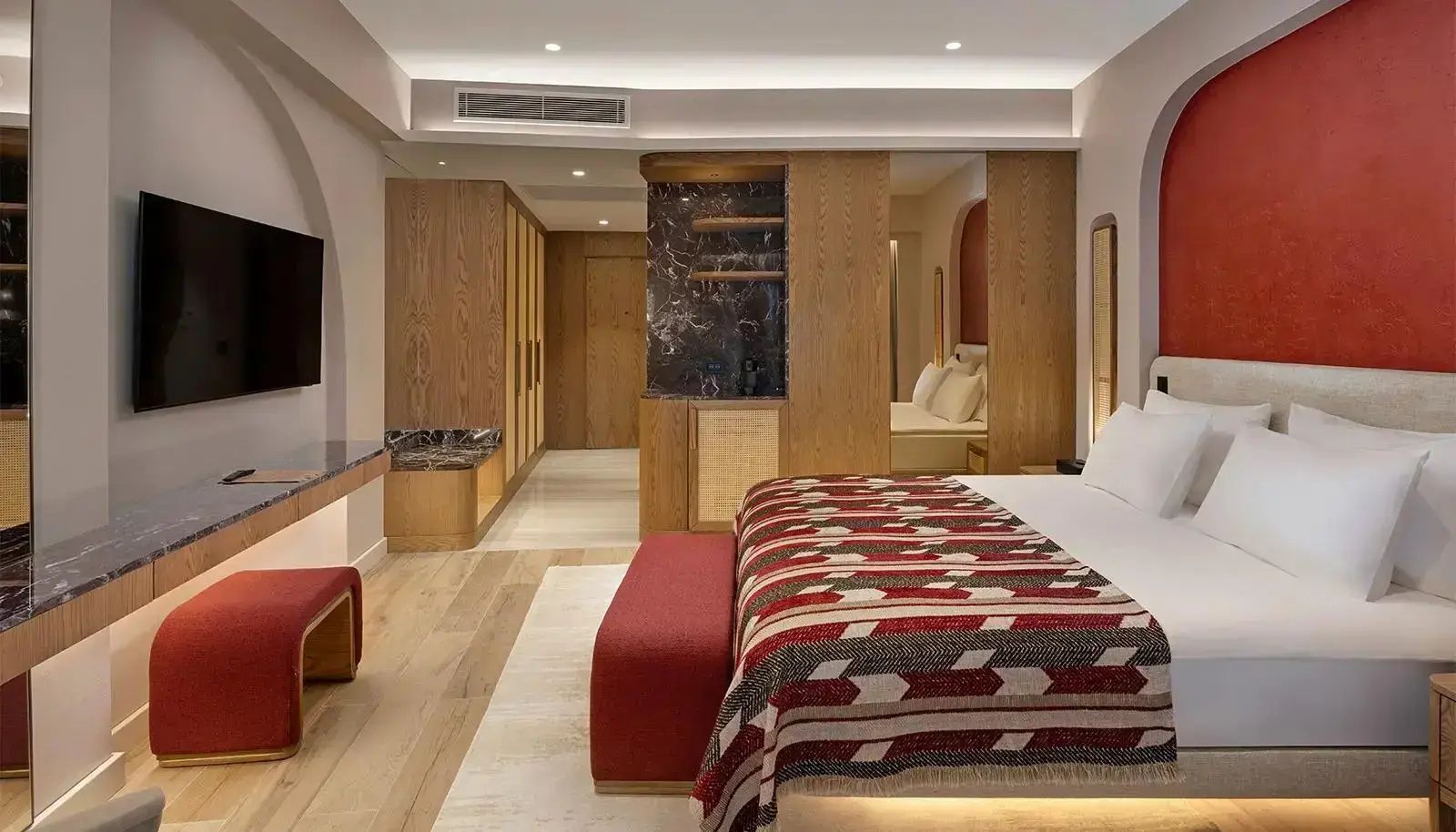 Blick auf das Doppelbett und die Holzschränke im Eingangsbereich des Hotelzimmers.