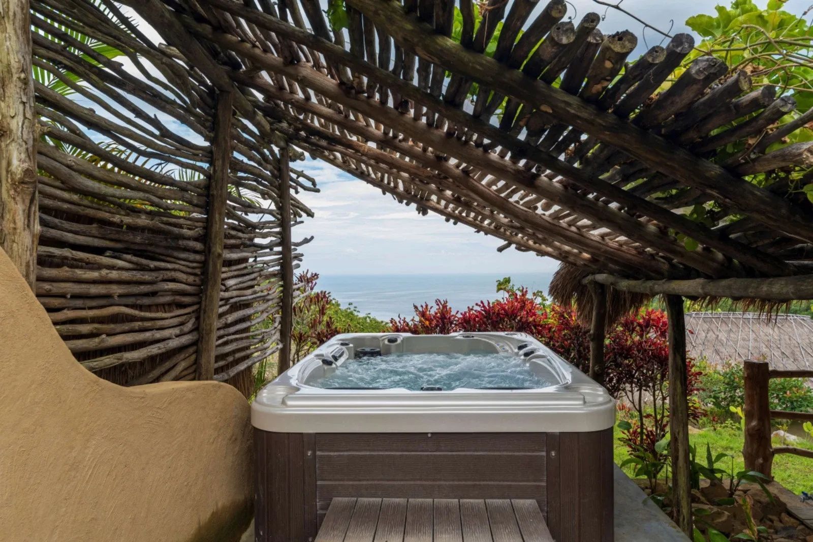Ein Whirlpool im Außenbereich unter einer Überdachung mit Blick auf das Meer.