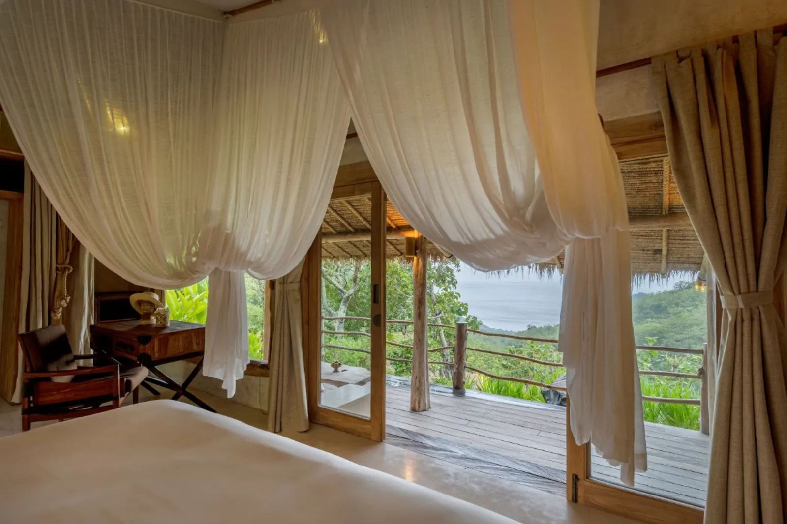 Blick aus dem Schlafzimmer mit weißem Baldachin auf die Terrasse und das Meer.