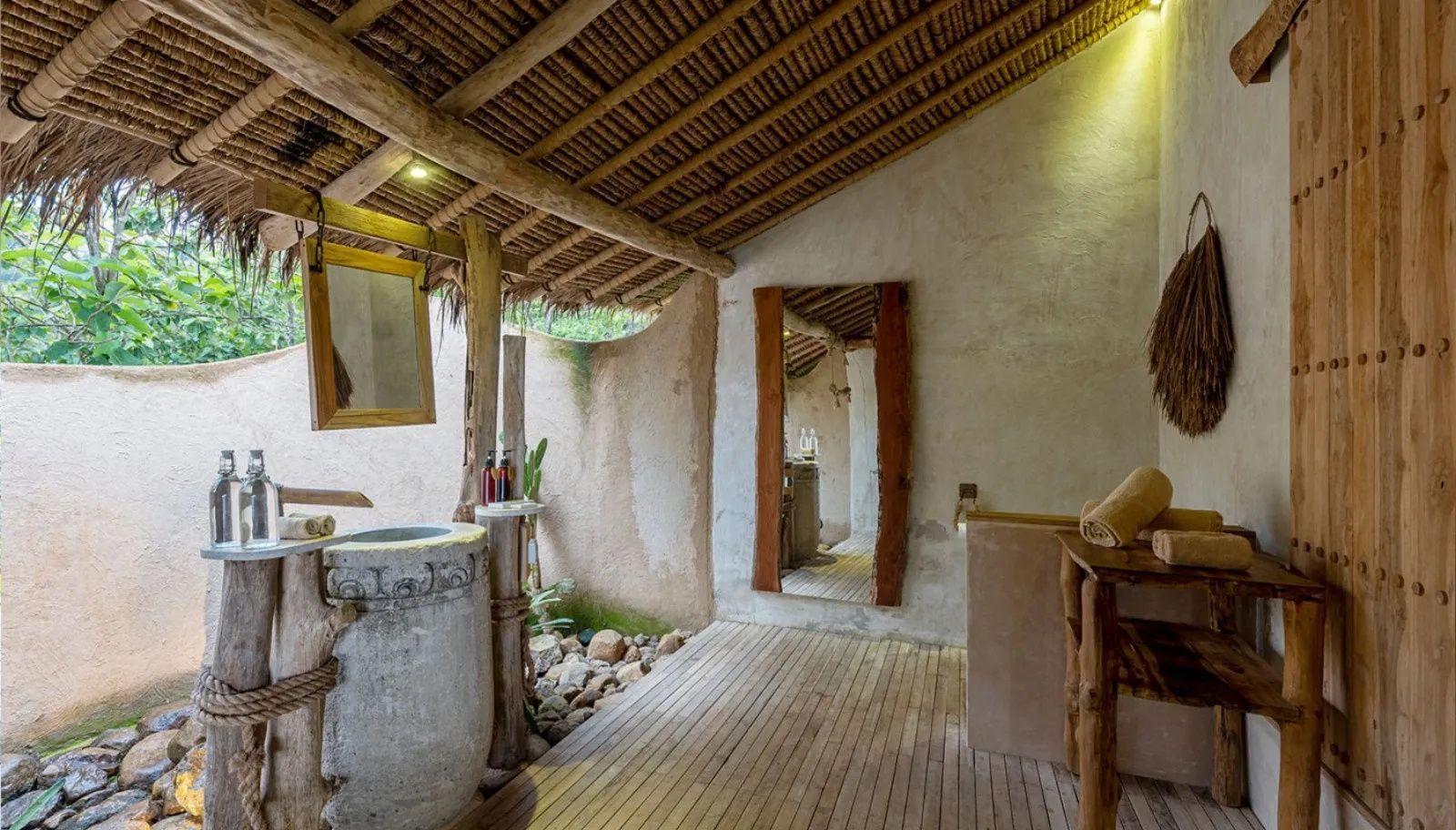 Offenes Badezimmer mit Steinwaschbecken, Holzboden und Strohdach